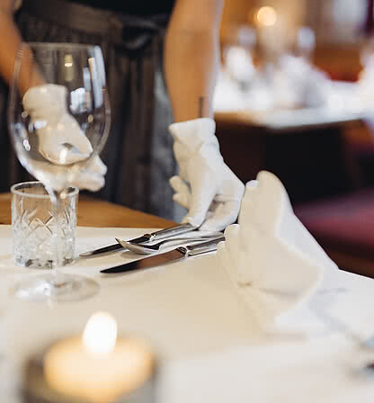 Service employee sets the table in the restaurant of the Hotel Vermala