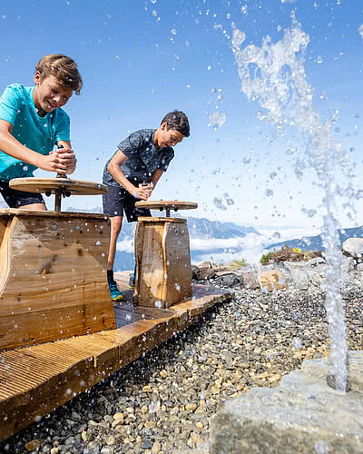 Two children playing with water on the Hochjoch adventure mountain